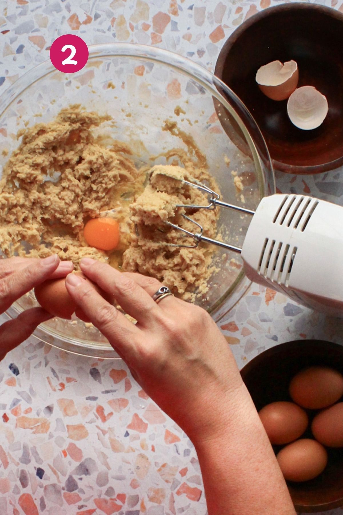 Hands cracking an egg into creamed butter and brown sugar batter for hojaldre añasqueño, Puerto Rican spice cake.