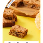 Peanut butter chocolate chip blondie squares on a yellow surface with a yellow flower and a striped wooden cutting board, framed in an arched Pinterest graphic layout with text reading "Classic Peanut Butter Chocolate Chip Blondies, Chewy and Buttery" and girlmeetsfire.com.