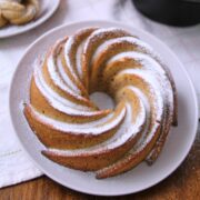 Puerto Rican spice cake hojaldre añasqueño displayed as a spiral bundt and mini bundts dusted with powdered sugar, surrounded by flowers and a lace doily.