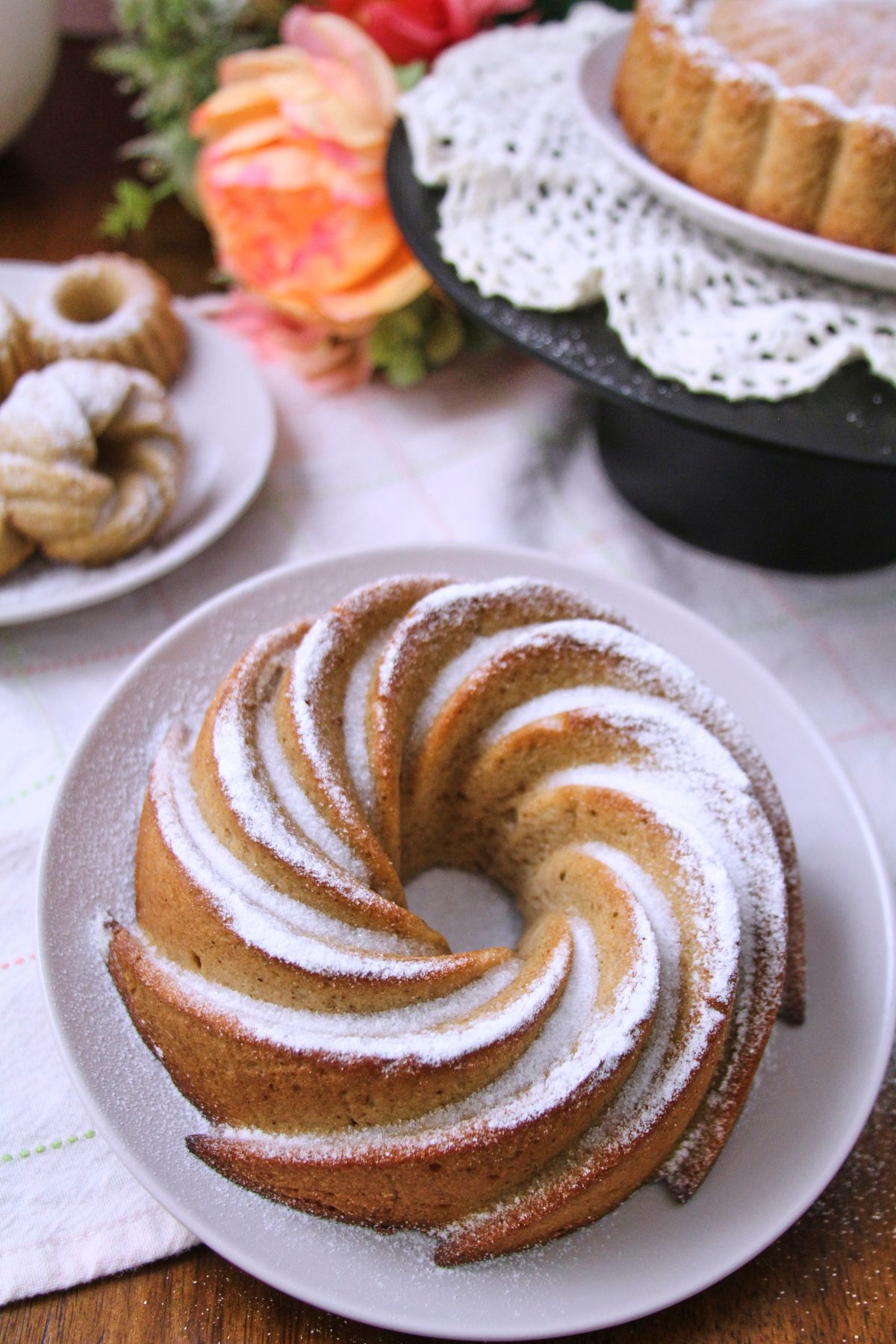 Hojaldre añasqueño Puerto Rican spice cake in a spiral bundt pan, dusted with powdered sugar, on a white plate on a wooden table.