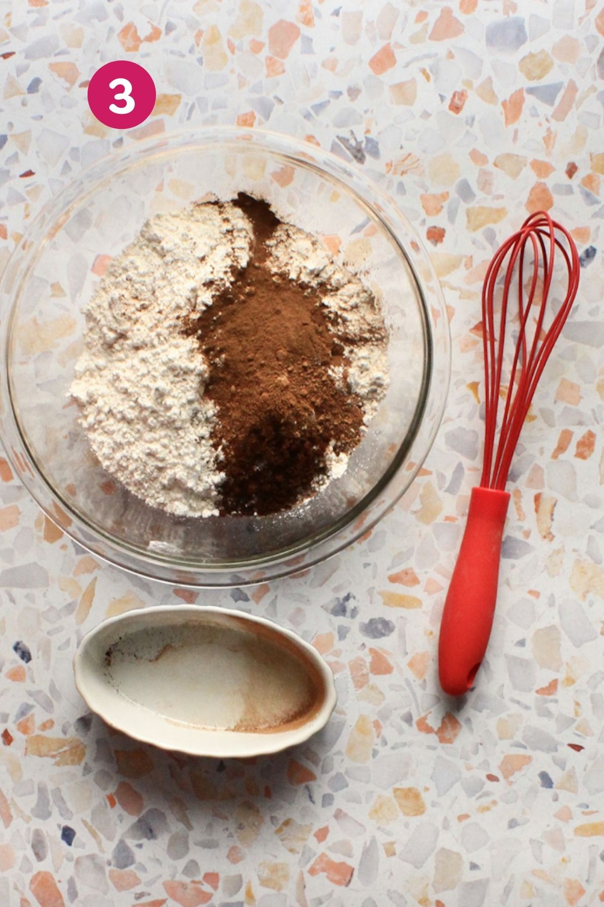 Glass bowl with triple-sifted flour and warm spices next to a red whisk, step three for hojaldre añasqueño Puerto Rican spice cake.