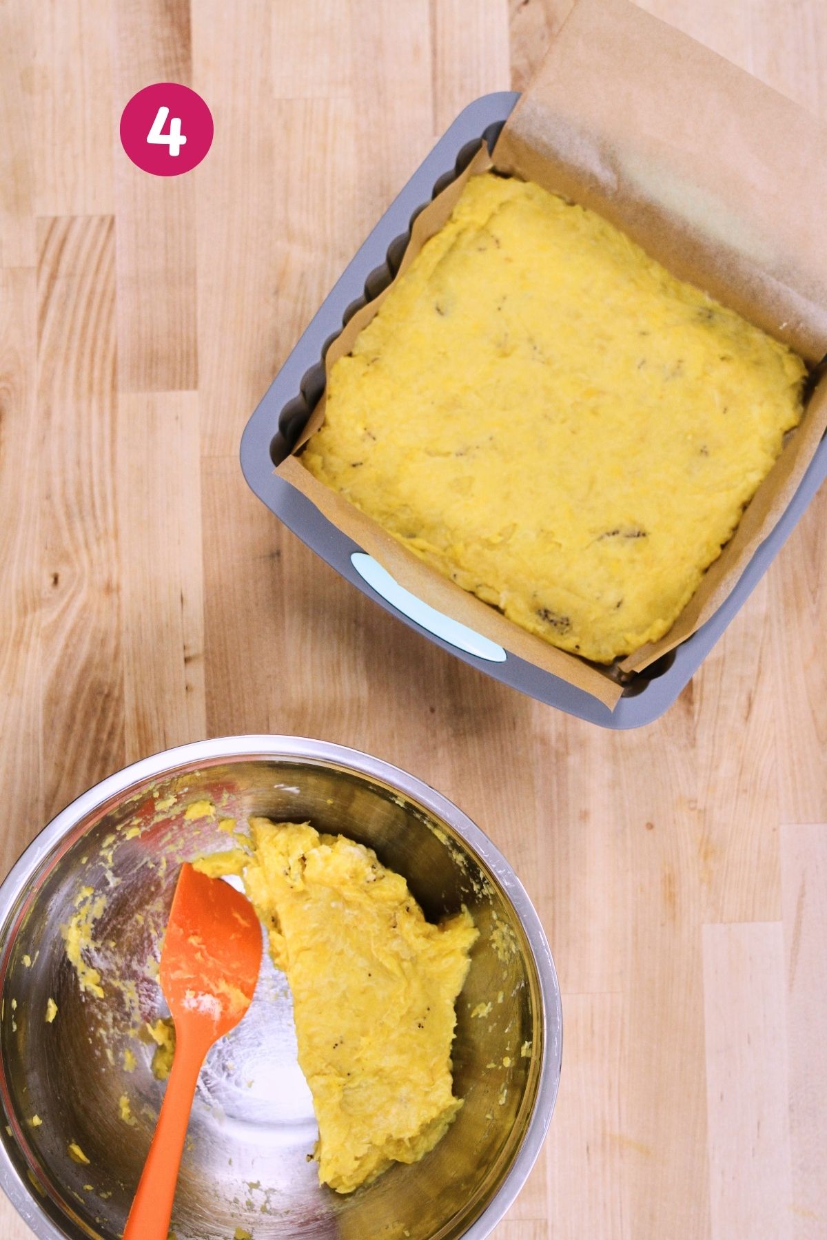 (Step 4 - mash pressed into pan) Mashed plantain base pressed into a parchment-lined baking pan with remaining mash in a mixing bowl alongside an orange spatula.