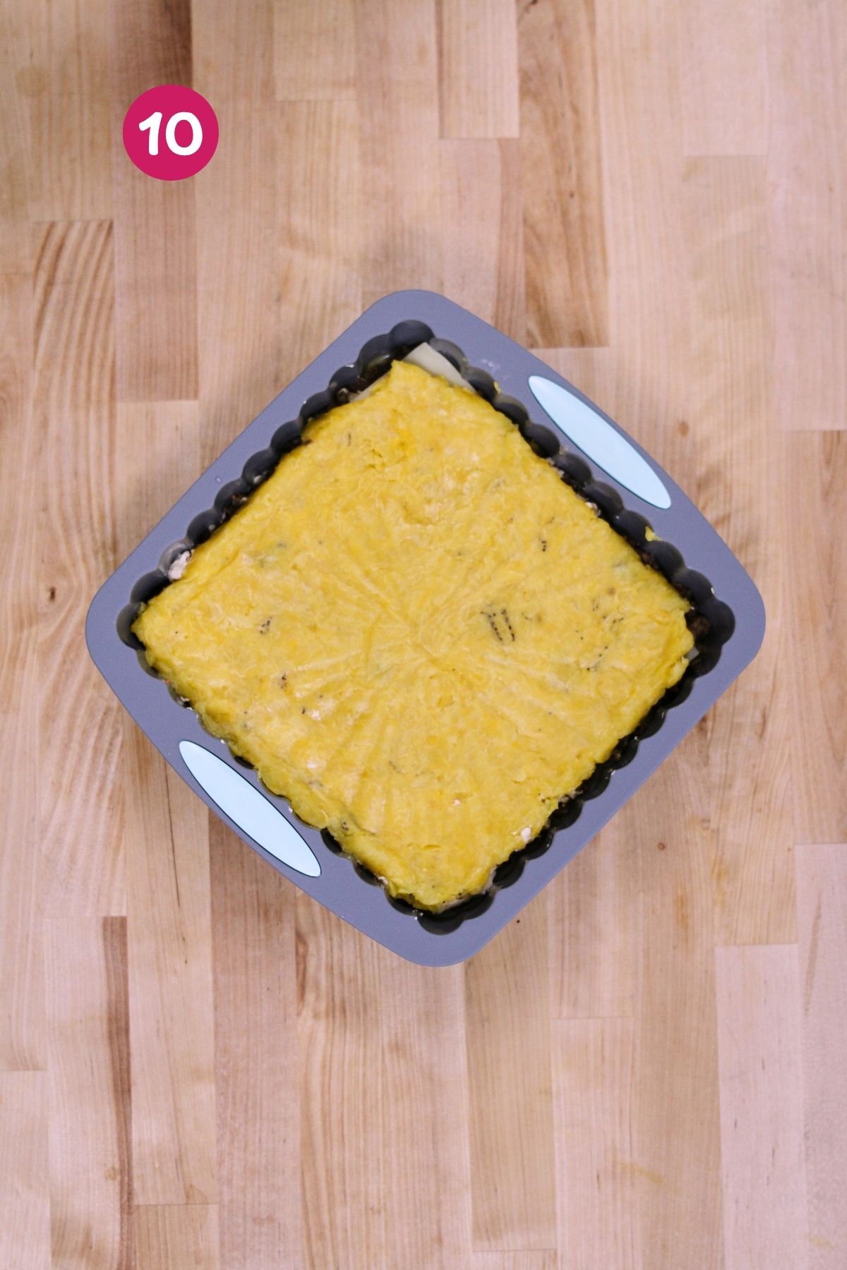 (Step 10) Top mashed plantain layer pressed over the filled baking pan, ready for egg wash and baking.