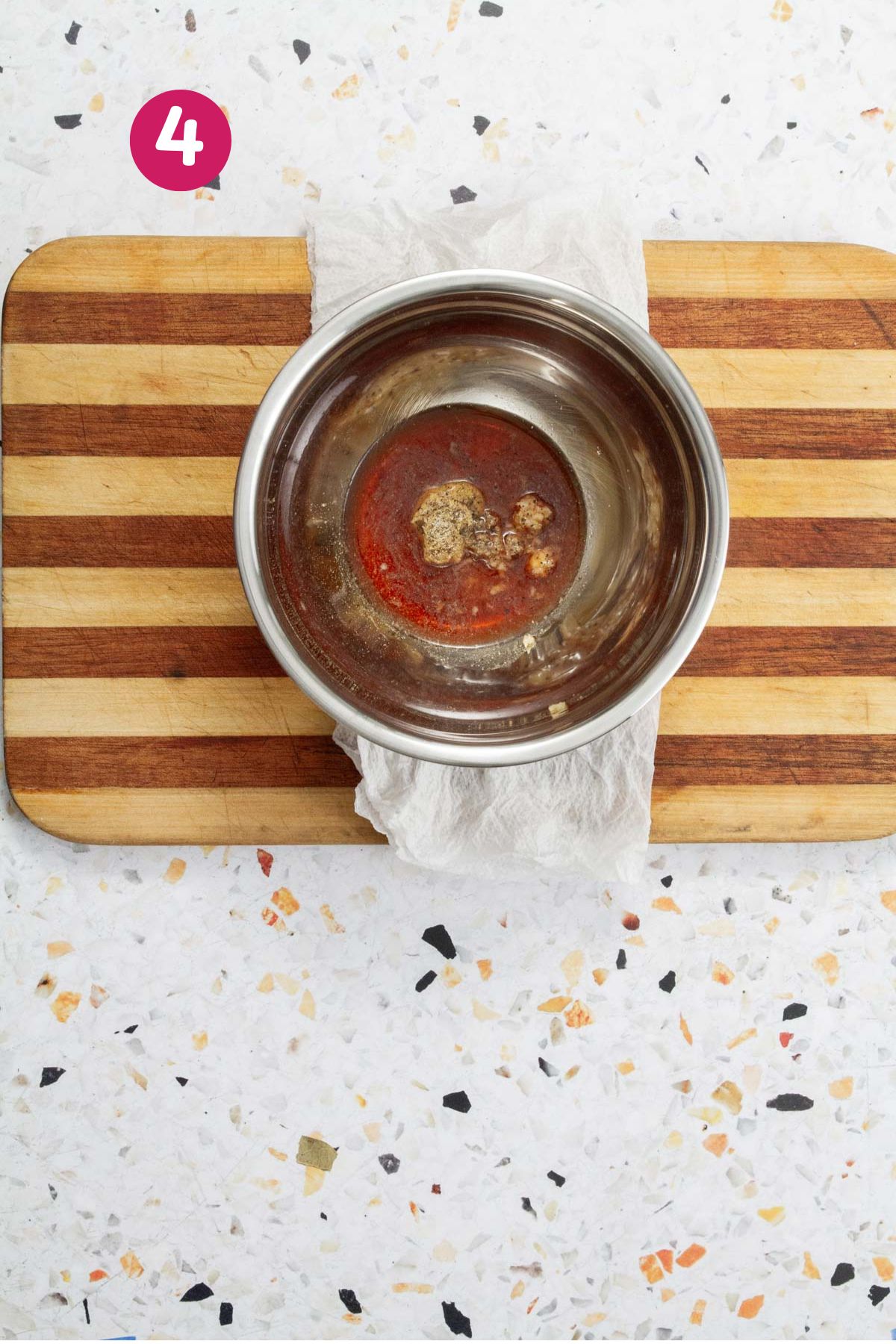 Vinegar, mustard, and spices are combined in a stainless steel bowl to make a pasta salad vinaigrette.